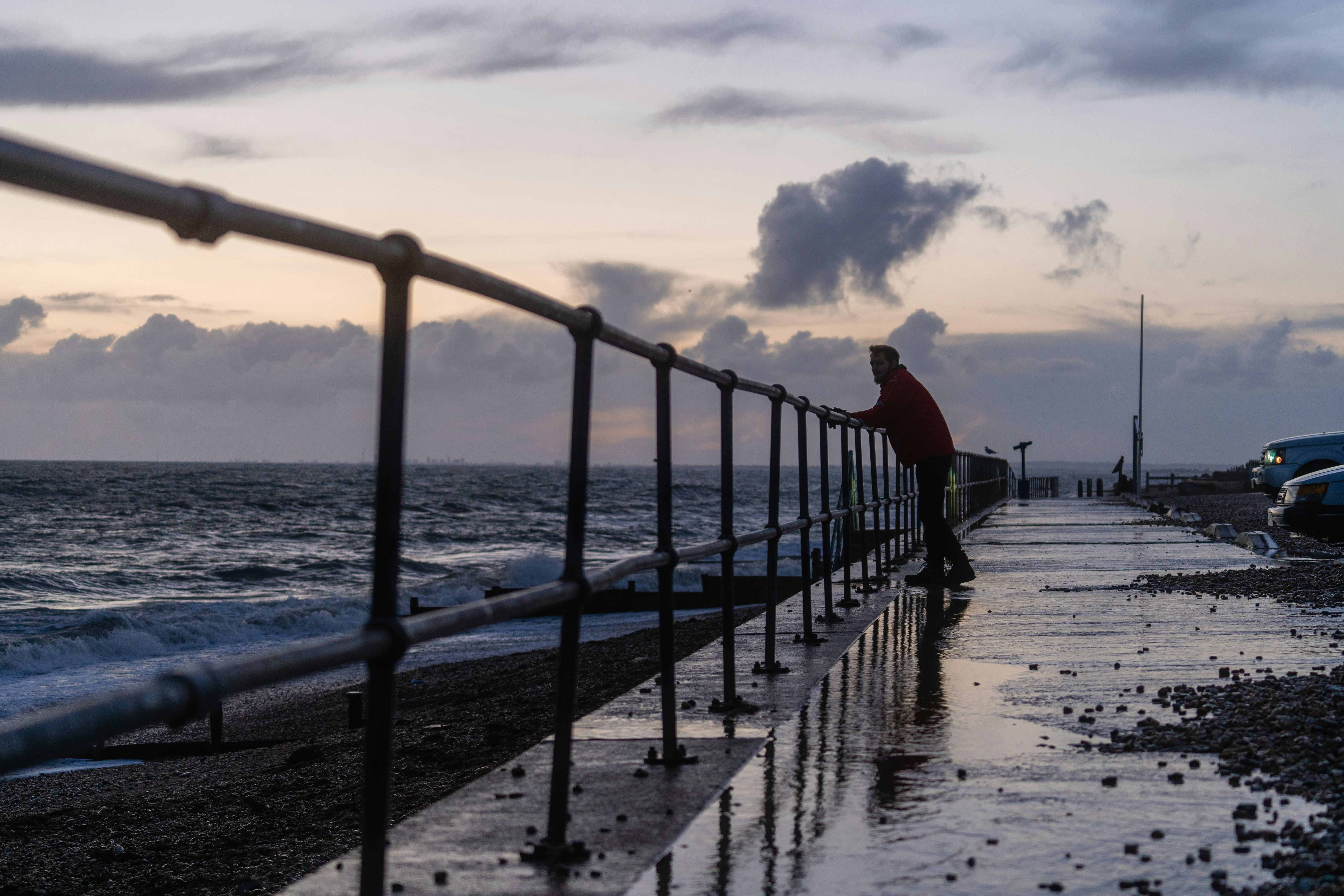 black metal railings on sea dock under white clouds during daytime